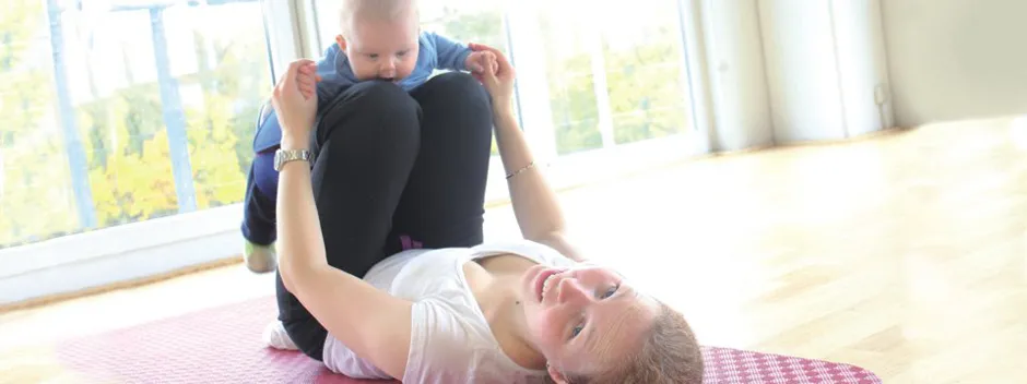 Mutter und Baby beim Yoga auf Matten